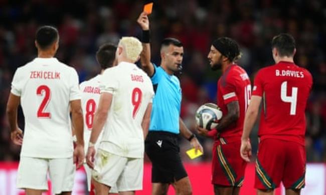 The referee, Rohit Saggi, shows a red card to Baris Yilmaz