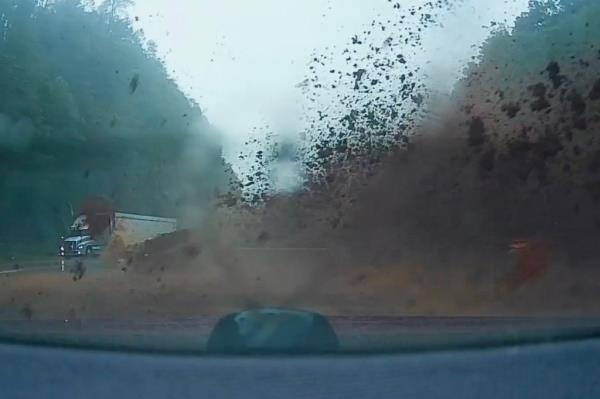 Dashcam view of a couple narrowly avoiding a mudslide on a dirt road in North Carolina's Blue Ridge Mountains during Hurricane Helene